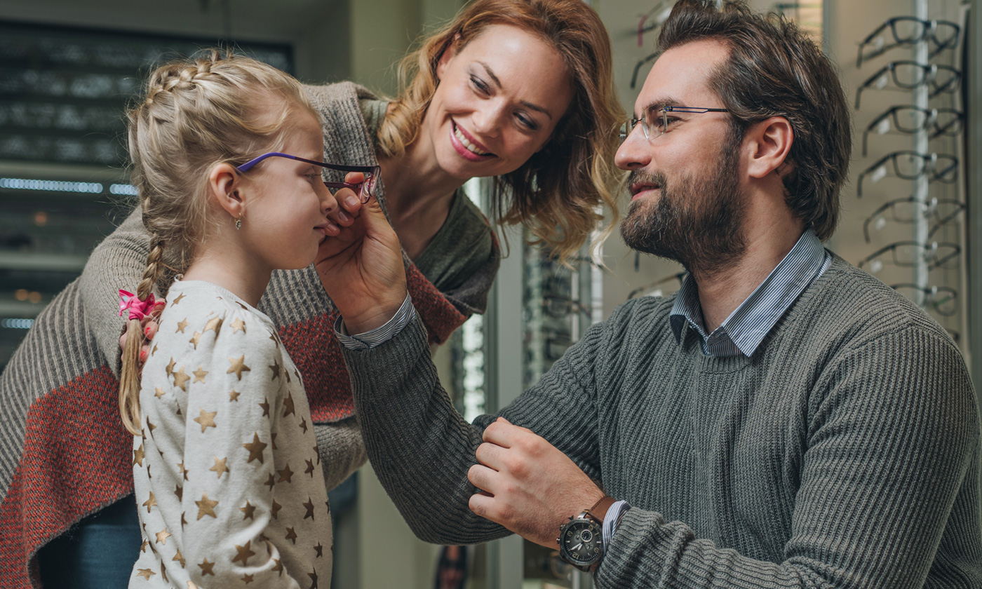 Father placing eyeglasses on daughter