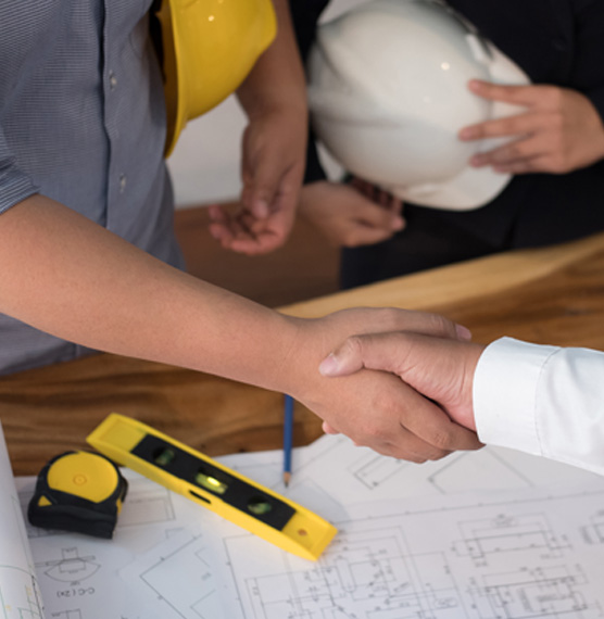 shaking hands over blueprints