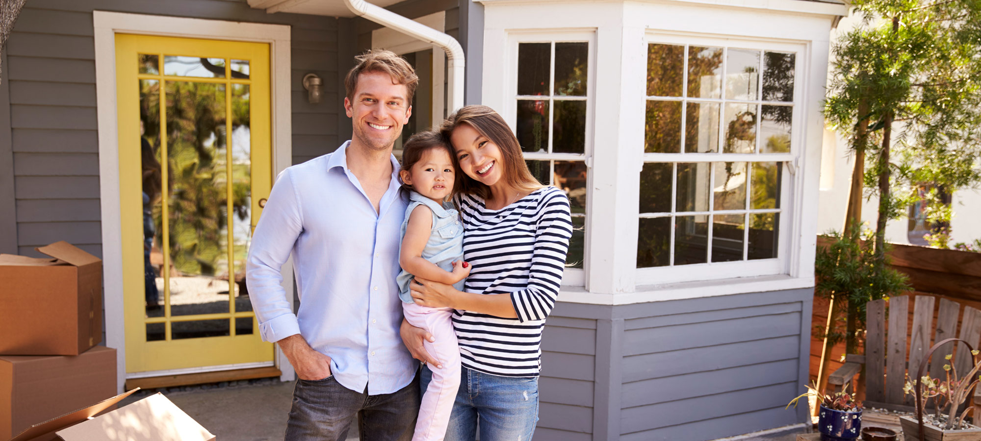 New Homeowners with child, unpacking in front of house