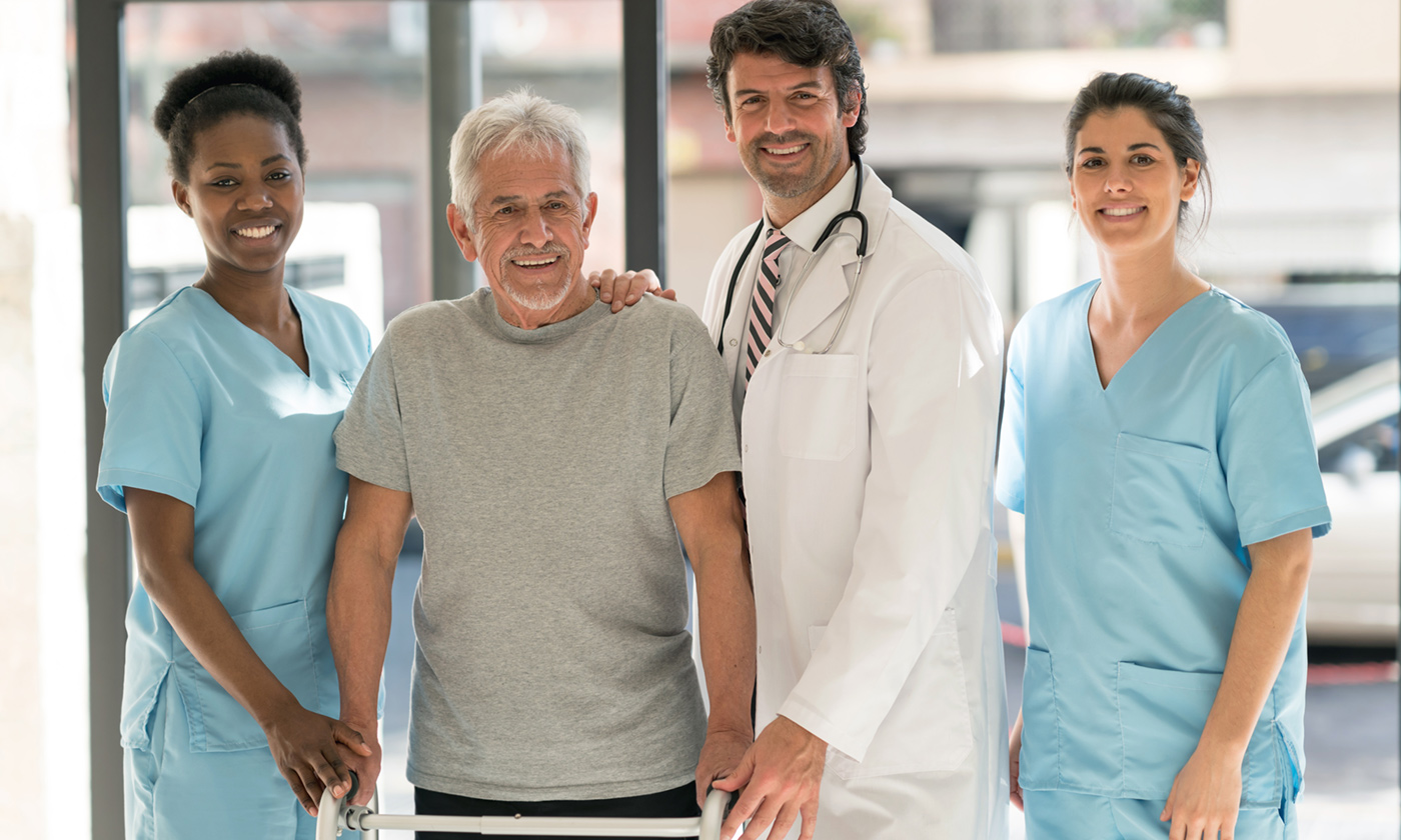 Hospital personnel helping elderly with walker